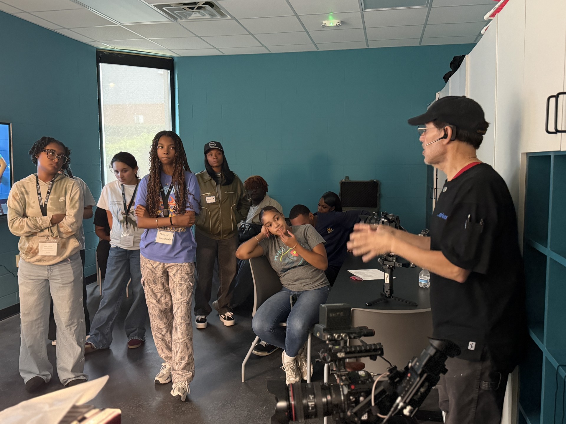 Students gathered around an instructor and camera equipment during a media workshop